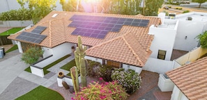 A residential building with a tiled roof, solar panels, and a cactus in the garden.