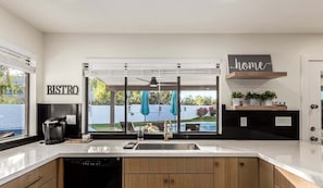Una cocina moderna con una isla grande, una cafetera y vista a un patio trasero.