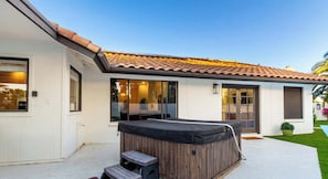 A modern house with a patio, a hot tub, and a covered outdoor seating area.