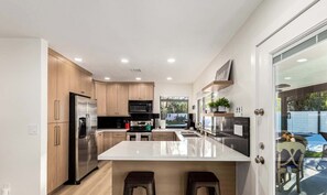Una cocina moderna con armarios de madera, electrodomésticos de acero inoxidable y una isla central.