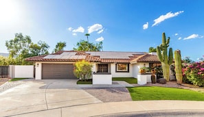 A single-story house with a garage, solar panels, and a well-maintained lawn.