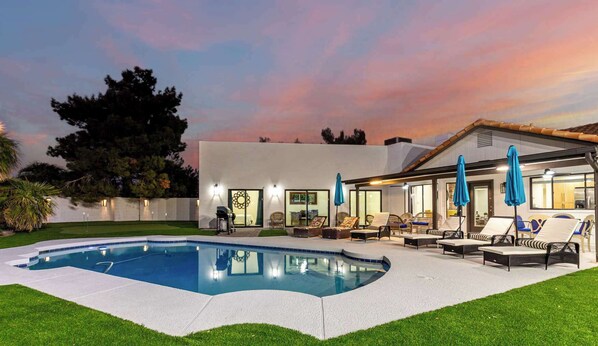 Una casa moderna con piscina, mobiliario exterior y zona de patio.