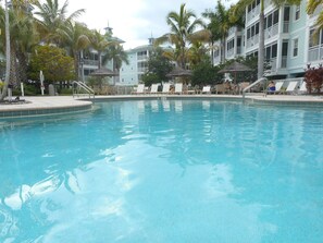 Ein Swimmingpool mit Liegestühlen und Palmen.