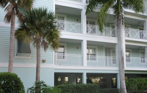 Ein mehrstöckiges Hotel mit hellblauer Fassade, weißen Balkonen und Palmen.