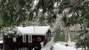 Eine Holzdiele mit verschneitem Deck und Blick auf einen See.