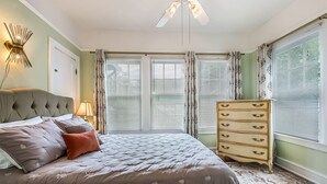 A bedroom with a large bed, a dresser, and a ceiling fan. - Riverbend Gem in Historic Carrollton Uptown  (New Orleans)