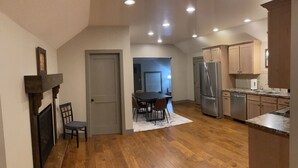 A spacious kitchen with wooden flooring, a dining area with a table and chairs, and a refrigerator.