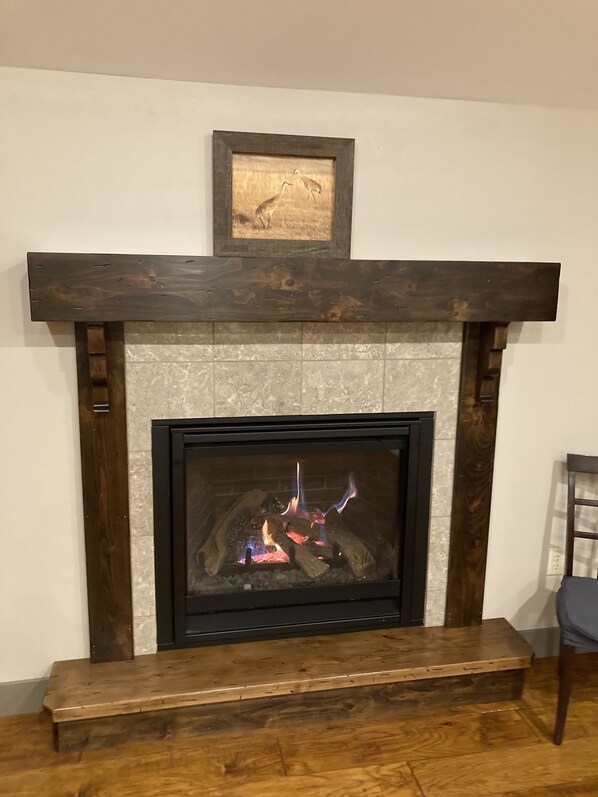 A fireplace with a stone surround, a wooden mantel, and a framed picture above it.