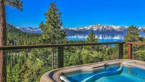 Un jacuzzi con vista despejada a un lago de montaña y el bosque circundante.