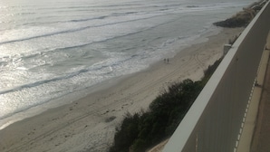 Vista costera con playa arenosa y olas del océano.