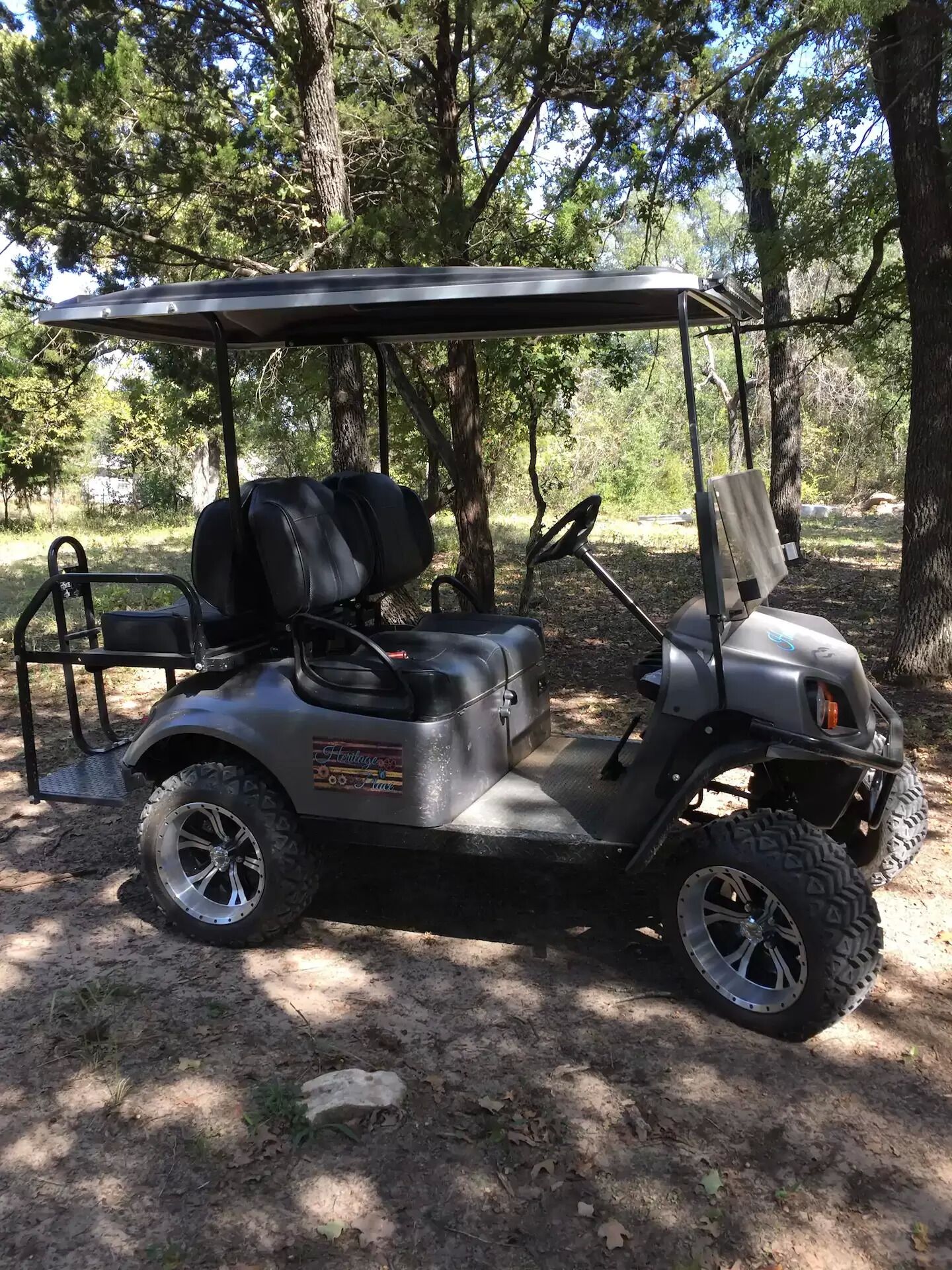 Un carrito de golf estacionado en un área boscosa con un dosel.