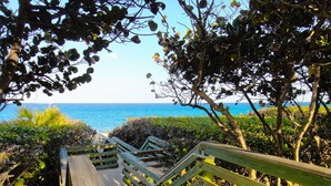 Un escalier en bois mène à une plage d’où l’on a une vue dégagée sur l’océan.