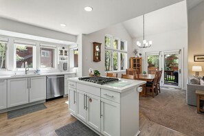 A modern kitchen with white cabinetry, a central island, and a dining area with wooden furniture.
