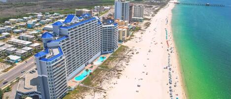 A coastal hotel with multiple buildings, a beach, and a pier.