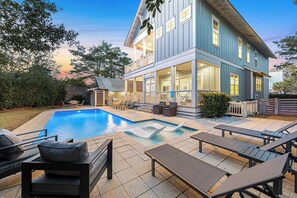 Ein zweigeschossiges Haus mit Swimmingpool, Außenbereich zum Sitzen und einer überdachten Terrasse.