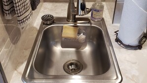 A stainless steel kitchen sink with a modern faucet, a soap dispenser, and a paper towel holder. - Finely Crafted Studio Apartment In The Heart Of Old Town (Fort Collins)