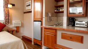 A compact kitchen with wooden cabinets, a built-in dishwasher, a sink, and a toaster. - Finely Crafted Studio Apartment In The Heart Of Old Town (Fort Collins)