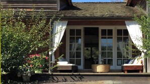 A wooden house with a porch, two chairs, a woven basket, and potted plants. -  Catskills Sanctuary  (Delancey)