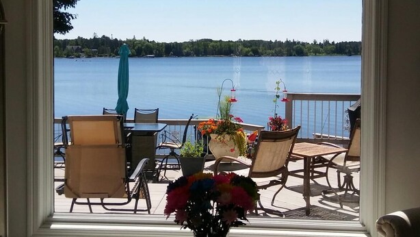 Una habitación con vista a un lago, una mesa con un florero y una zona de estar con sillas y una mesa.