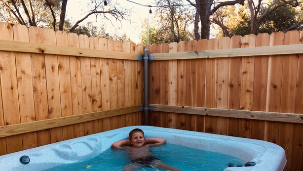 A hot tub in a backyard with a wooden fence.