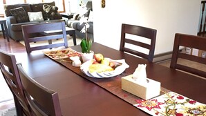 A dining table set with a fruit plate, a potted plant, and a tissue box.