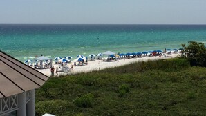 Ein Strand mit Reihen von blauen und weißen Sonnenschirmen, einem sandigen Ufer und Blick auf den Ozean.