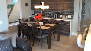 Una cocina moderna con armarios de madera oscura, una isla central y un comedor con mesa y sillas.