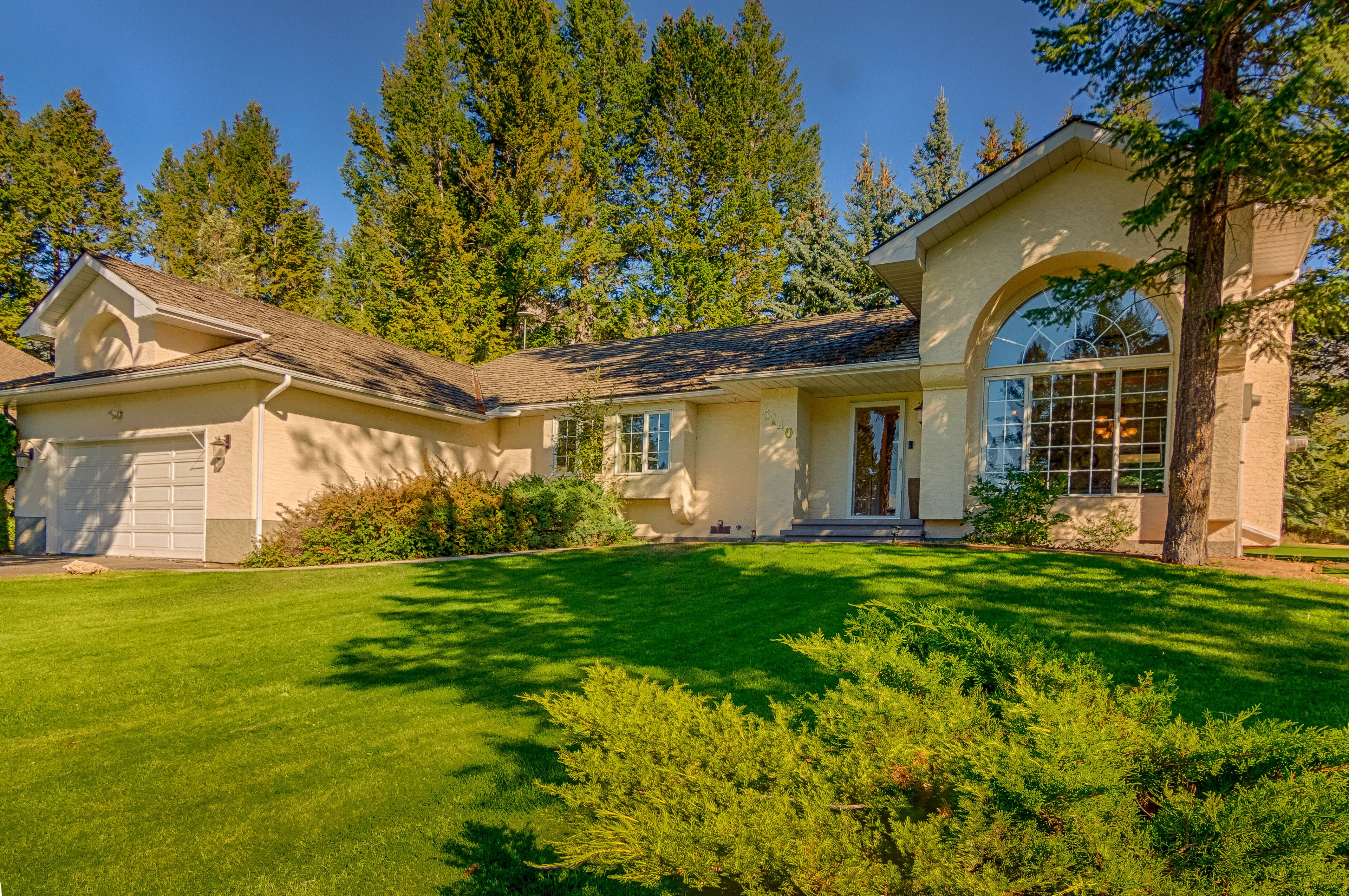 A two-story house with a garage, a large front window, and a well-maintained lawn.