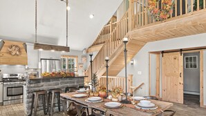 A spacious kitchen with a stone island, wooden staircase, and a dining area set for a meal. - Summer DISCOUNT Belleayre Mountain House, Catskills (Fleischmanns Heights)