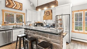 A modern kitchen with a large island, white cabinets, and a stone accent wall. - Summer DISCOUNT Belleayre Mountain House, Catskills (Fleischmanns Heights)