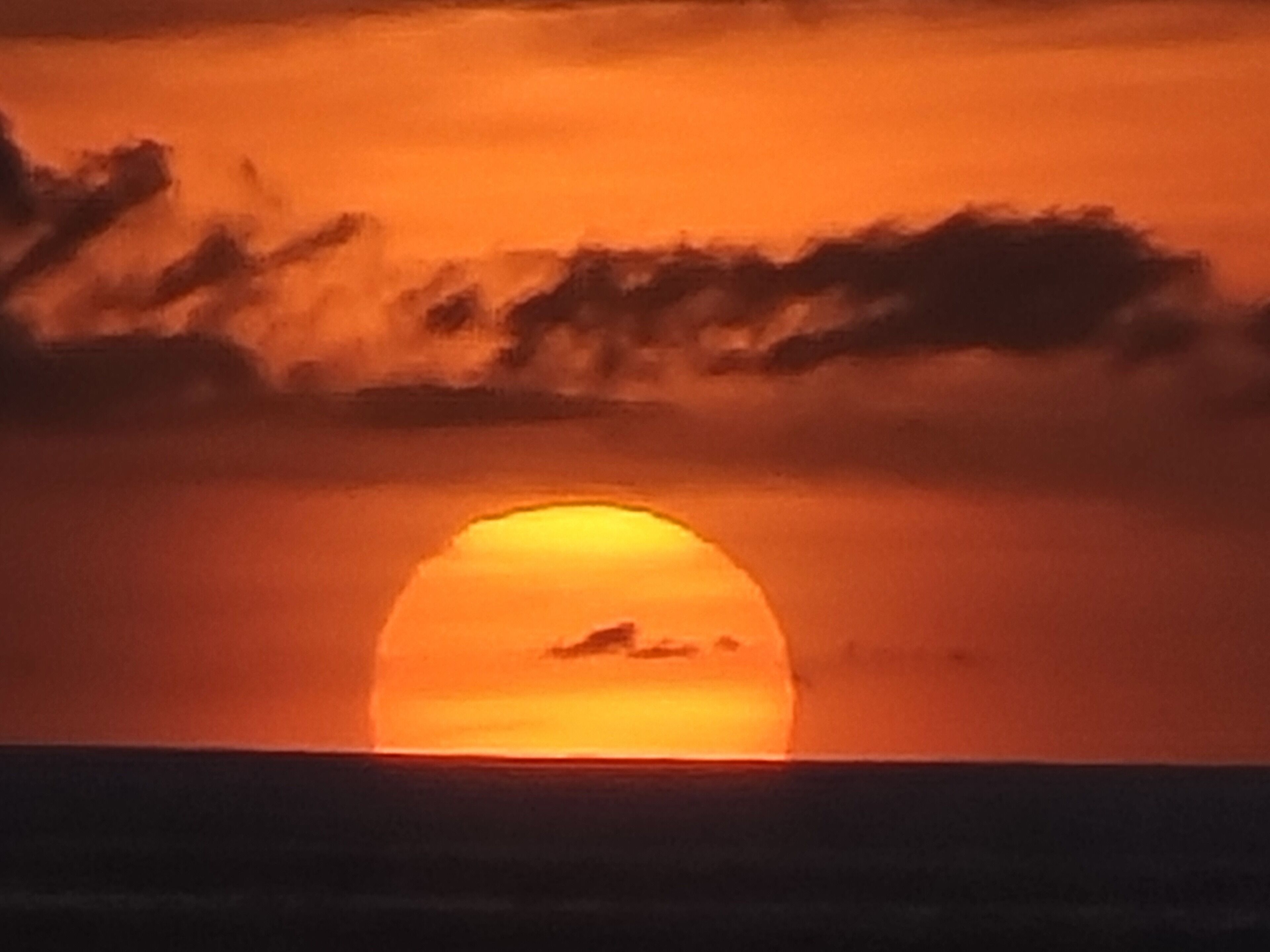 Un atardecer sobre el océano con cielo despejado.