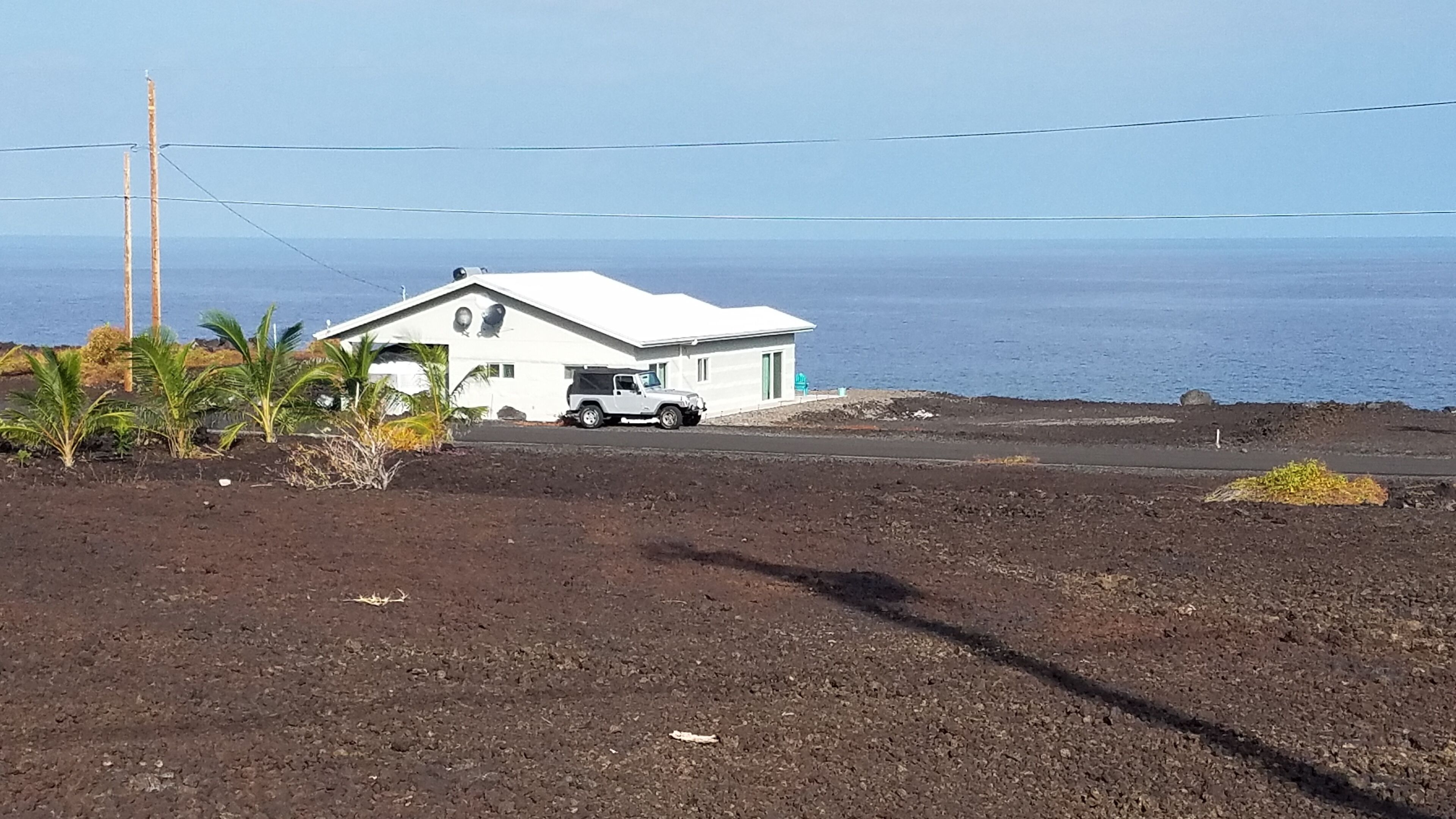 Una casa bianca con un garage, un camion parcheggiato e vista sull'oceano.