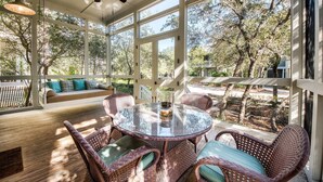 A covered outdoor seating area with wicker furniture, a glass table, and a ceiling fan. - Coastal Chic Home with Exquisite Design, Outdoor Living, Golf Cart & Watercolor Beach Club Access (Santa Rosa Beach)