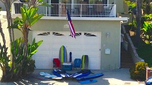 Una casa de dos pisos con una puerta de garaje, una bandera estadounidense y varios kayaks y tablas de remo afuera.