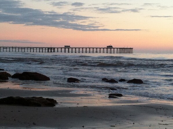 Un muelle que se adentra en el agua, con un atardecer de fondo.