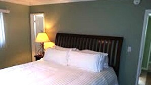 Una cama bien hecha con sábanas blancas en una habitación con paredes verdes y cabecero de madera.