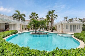 Una piscina rodeada de palmeras y edificios blancos con balcones.