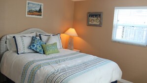 A neatly made bed with patterned bedding, a bedside lamp, and wall art.