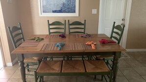 A dining table with four chairs, a framed artwork above, and a door to the right.