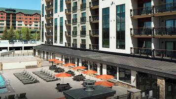 A hotel exterior with a swimming pool, outdoor seating, and multiple balconies.
