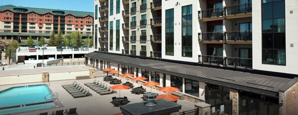 A hotel exterior with a swimming pool, outdoor seating, and multiple balconies.
