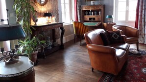 A traditional living room with a leather sofa, a wooden coffee table, a billiards table, and a bookshelf.