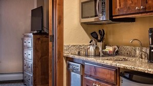 A kitchen with wooden cabinets, a microwave, a kettle, and a dishwasher.