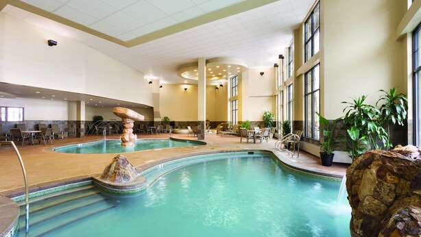 A large indoor swimming pool with multiple seating areas and a waterfall feature.