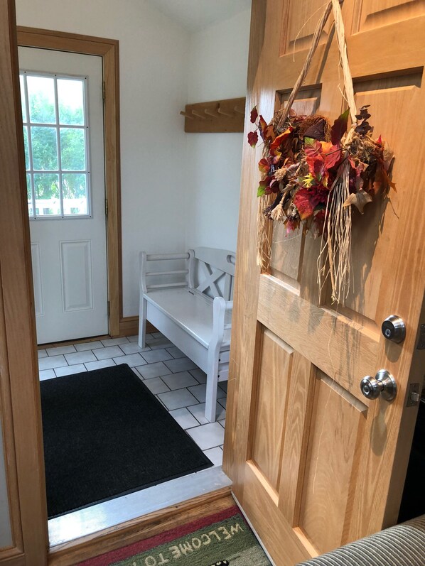 A wooden door with a doormat reading "WELCOME TO" and a bench in the background. - Charming Mountain Retreat Lg Mod/Kit on Stream/Fire-pit/Hot Tub (Windham)