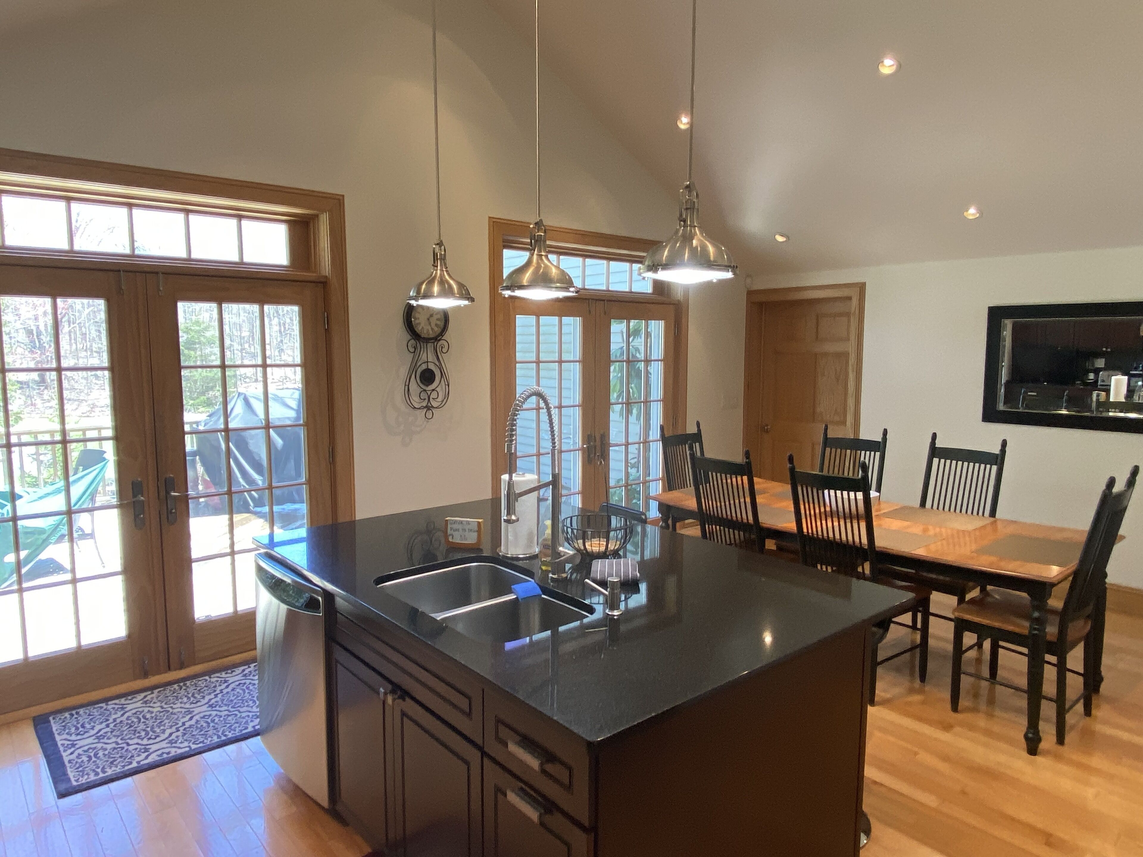 A modern kitchen with a large island, double doors, and a dining area with a wooden table and chairs.