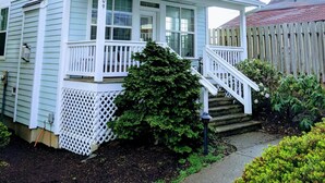 A two-story house with a front porch, a small staircase, and a picket fence.