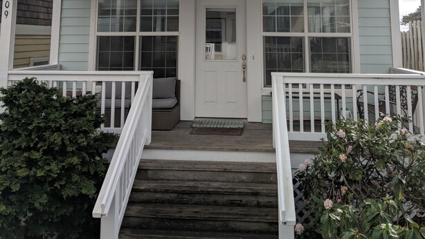 A two-story house with a front porch, a door with a window, and a mailbox.