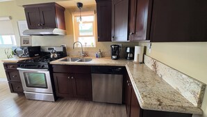 A kitchen with dark wood cabinets, stainless steel appliances, a granite countertop, and a window with a view.