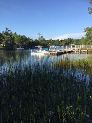 A calm lake with boats docked at a wooden pier, surrounded by dense greenery.